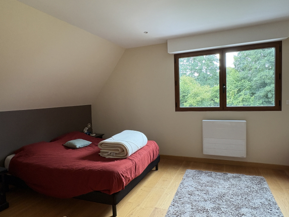 Chambre d'une propriété avec lit double et vue sur la verdure à Saint-Étienne-la-Thillaye, Normandie.