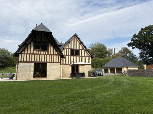 Maison à colombages avec jardin dans un cadre verdoyant en Normandie.