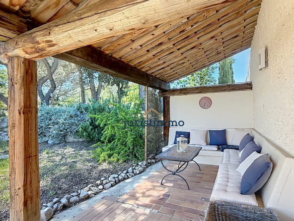 Terrasse avec canapé et table, entourée de verdure et d'arbres