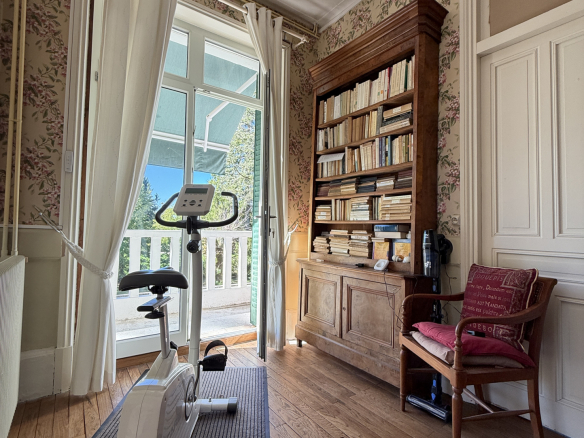Interior of a property with an exercise bike, a library and a door leading outside.