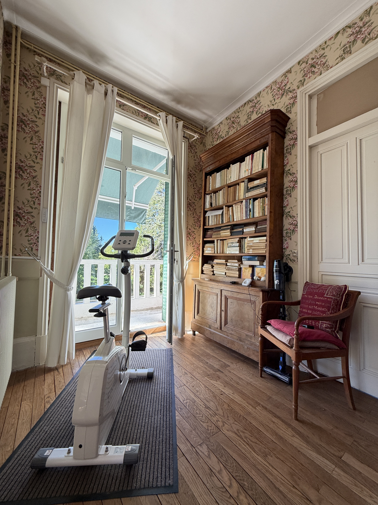 Interior of a property on the banks of the Ain River Interior of a property with an exercise bike, a library and a door leading outside.