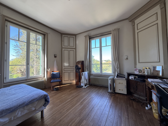 Spacious room with windows overlooking a wooded park.