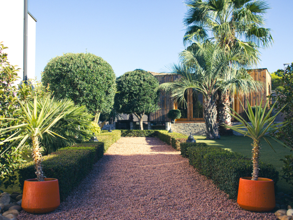 Driveway leading to a contemporary villa with a wooded garden in Narbonne.