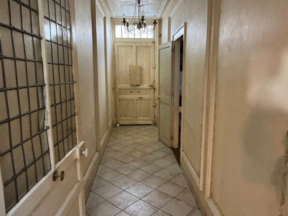 Entrance hall of a mansion in Lille, with tiling and light-colored walls.