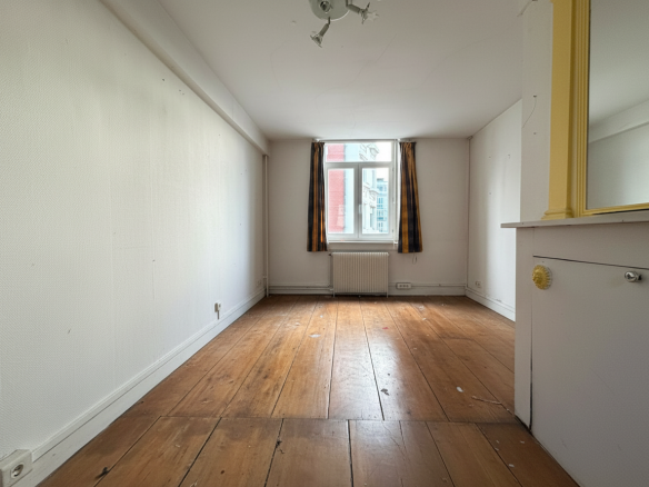 Interior of a manor house in Lille, with a wooden floor and a window illuminating the room.