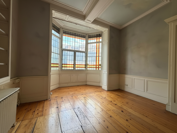 Interior of a manor house with stained-glass windows and wooden parquet flooring.