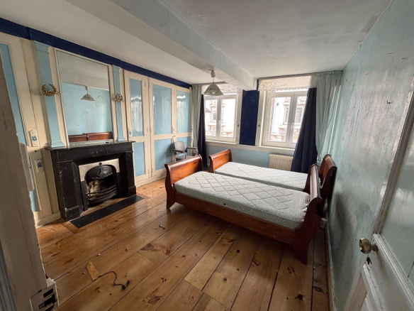 Room in a manor house in Lille, with two beds, fireplace and cupboards.