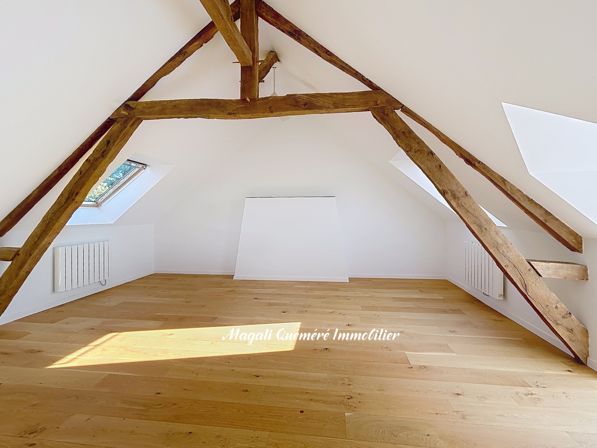 Intérieur rénové sous combles Intérieur d'une pièce sous les combles avec poutres apparentes et parquet en bois.