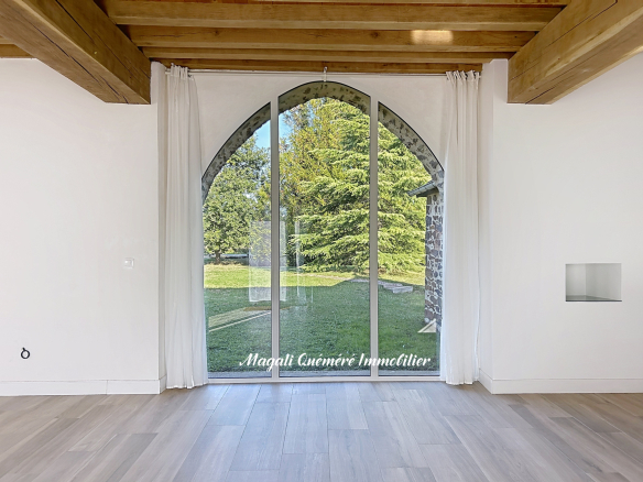 Intérieur d'une longère rénovée avec une grande baie vitrée donnant sur un jardin.