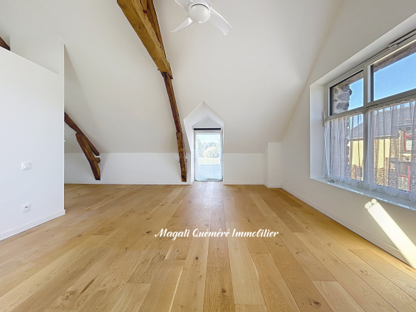 Intérieur d'une pièce rénovée avec poutres apparentes et parquet en bois.