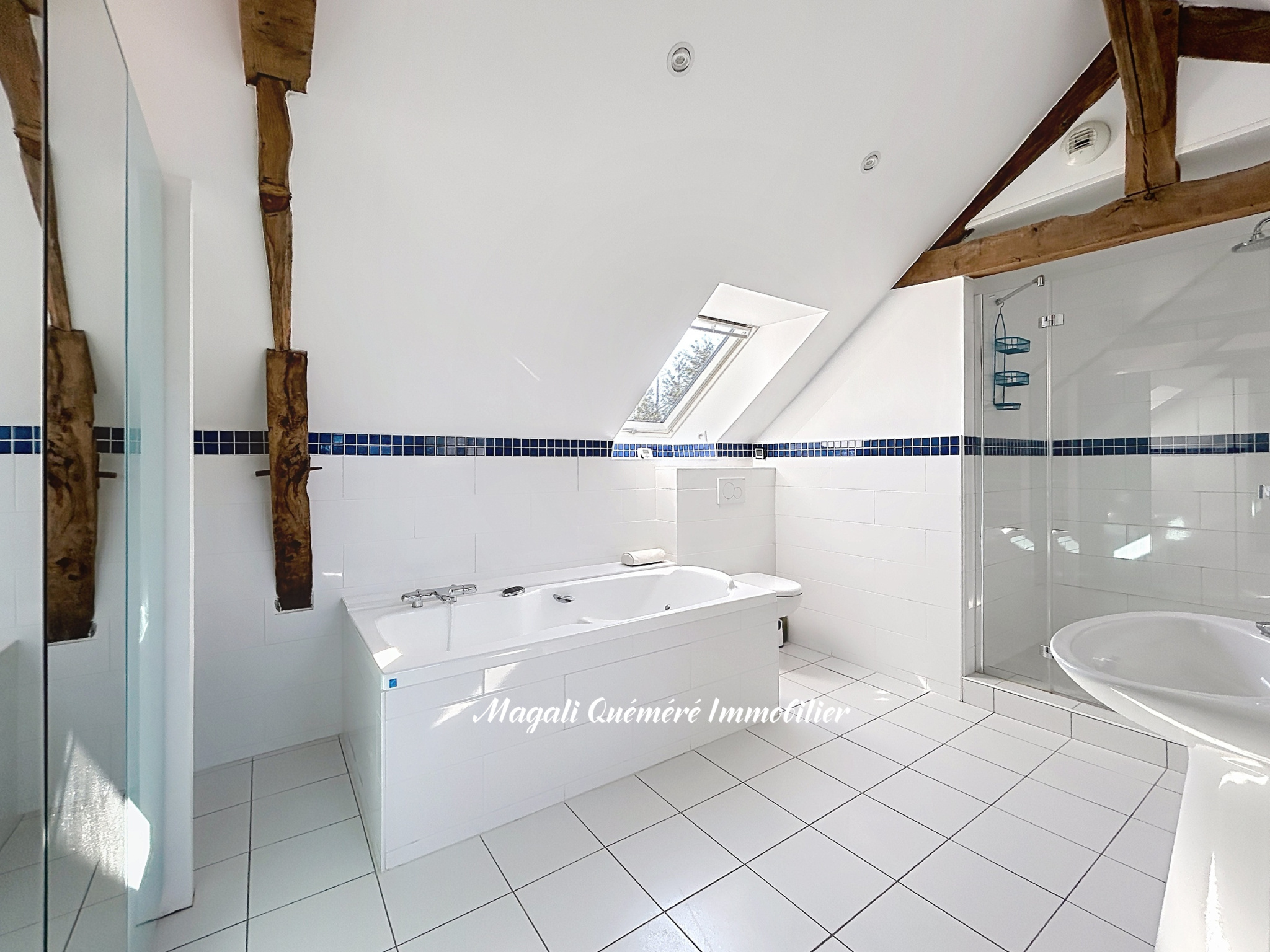 Salle de bain rénovée Salle de bain moderne avec baignoire et douche, poutres apparentes, éclairage naturel