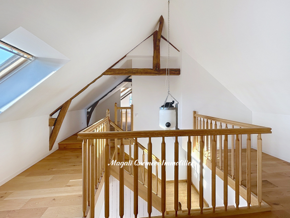 Intérieur d'une longère rénovée avec balustrade en bois et éclairage naturel