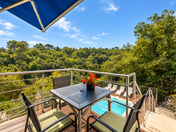 Terrasse avec table et chaises surplombant une piscine et une végétation luxuriante à Saint-Jeannet.