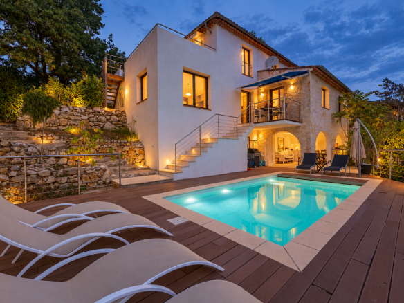 Villa avec piscine et terrasse à Saint-Jeannet, entourée de verdure au crépuscule.