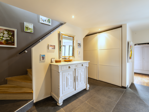 Intérieur d'une maison avec escalier en bois et meubles blancs, lumière naturelle