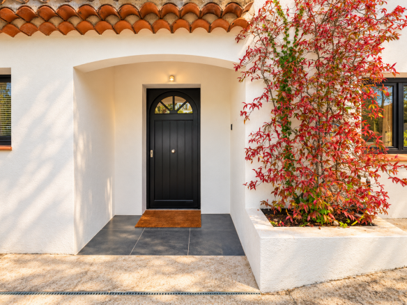 Entrée d'une villa moderne avec porte noire et plante grimpante à Saint-Jeannet.