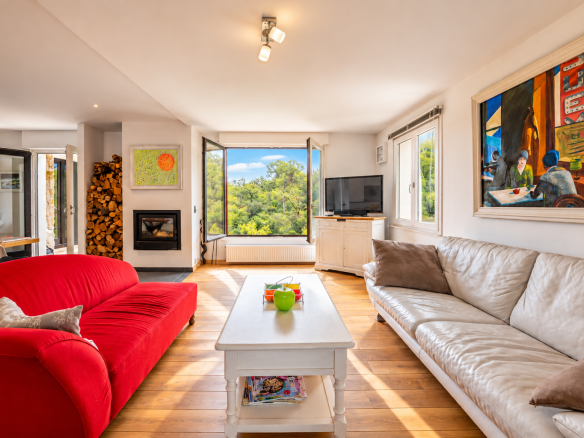 Intérieur d'une villa à Saint-Jeannet avec salon lumineux, canapé rouge et vue sur la nature.