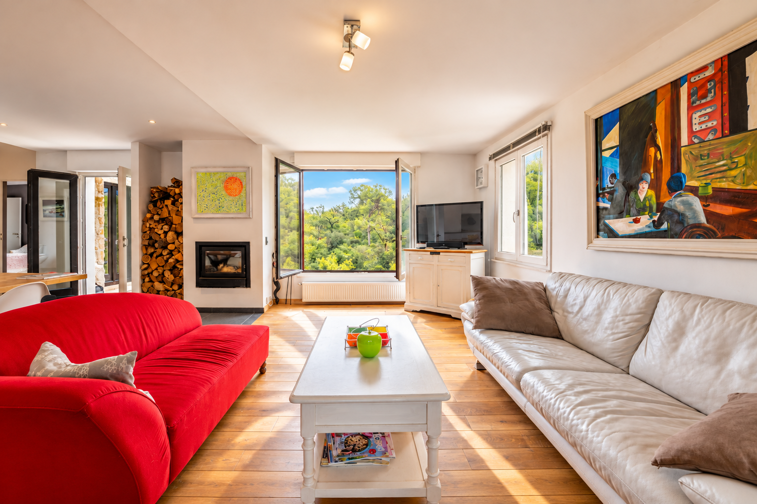 Intérieur d’une villa à Saint-Jeannet Intérieur d'une villa à Saint-Jeannet avec salon lumineux, canapé rouge et vue sur la nature.
