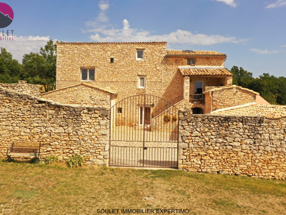 Propriété en pierre avec cour intérieure et murs en pierre, entourée de verdure à Bédoin.