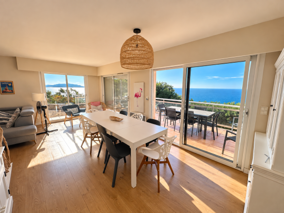 Intérieur d'une villa avec vue sur la mer, salle à manger lumineuse et accès à une terrasse.