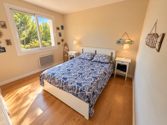 Chambre d'une villa avec lit double et fenêtre donnant sur l'extérieur.