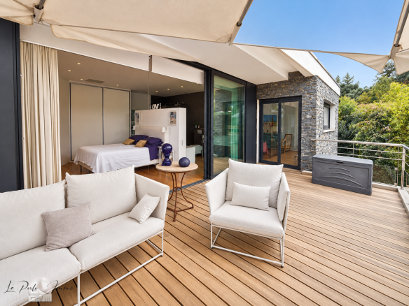 Terrasse en bois avec mobilier moderne, vue sur un jardin arboré, villa contemporaine à Perpignan.