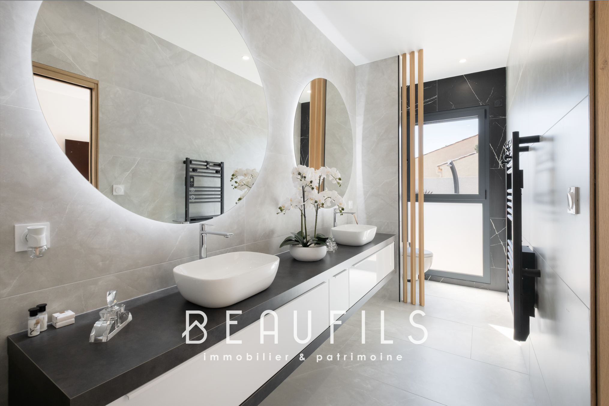 Salle de bain moderne avec vasques et miroir rond, lumière naturelle