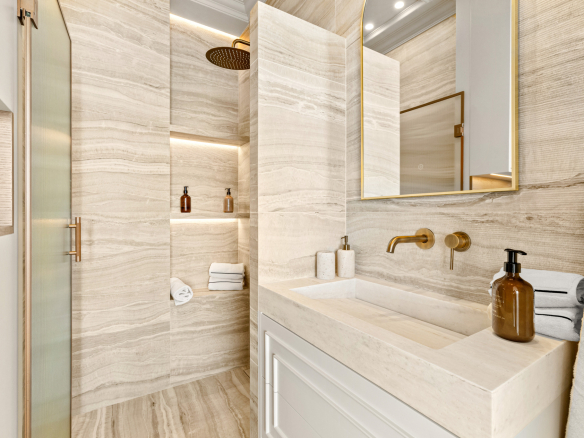Modern bathroom with stone walls and gold fixtures, soft lighting.