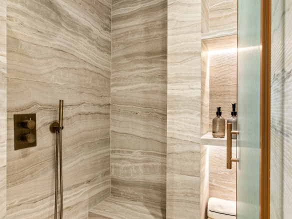 Modern bathroom with beige stone shower and integrated lighting.