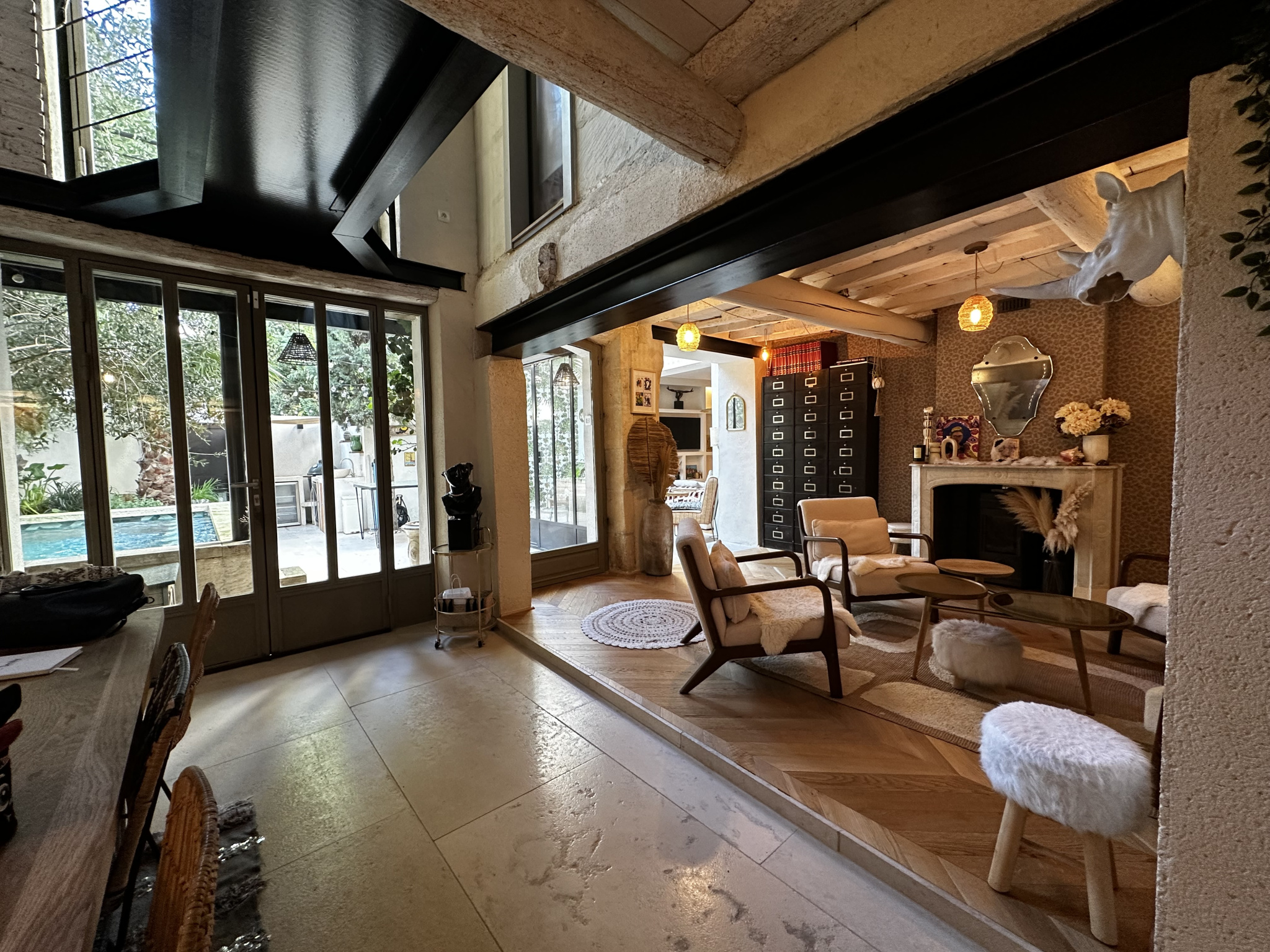 Intérieur d’une maison de village Intérieur d'une maison de village avec un salon lumineux et une cheminée, accès à une cour avec piscine.