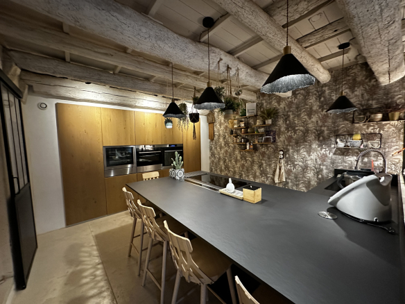 Cuisine moderne et spacieuse avec un îlot central et des éléments en bois, dans une maison de village.