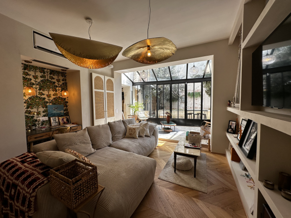Intérieur d'une maison de village rénovée, avec un salon lumineux et une véranda.