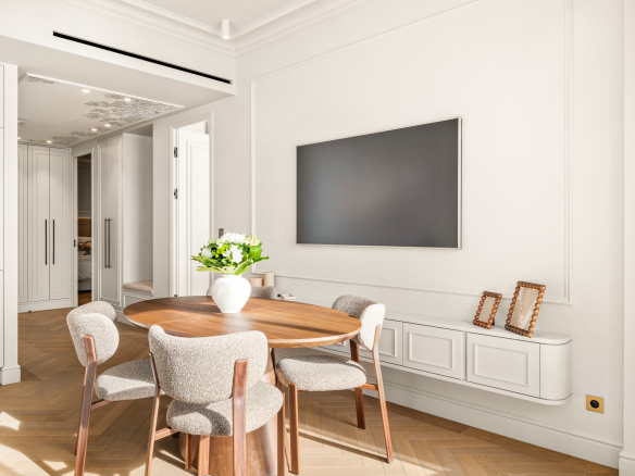 Intérieur d'un appartement rénové avec une table ronde et un écran au mur.
