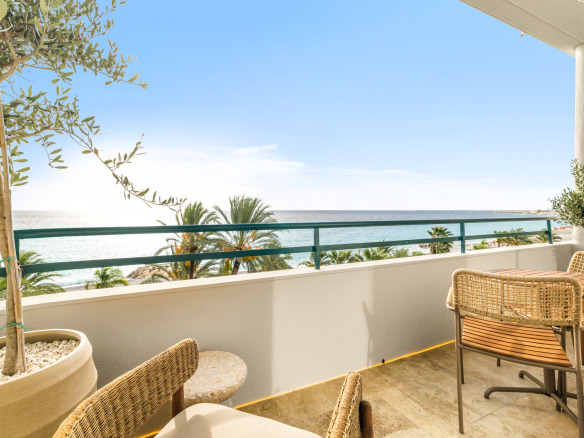 Balcon d'un appartement avec vue sur la mer Méditerranée à Nice, arbres et plage en arrière-plan.