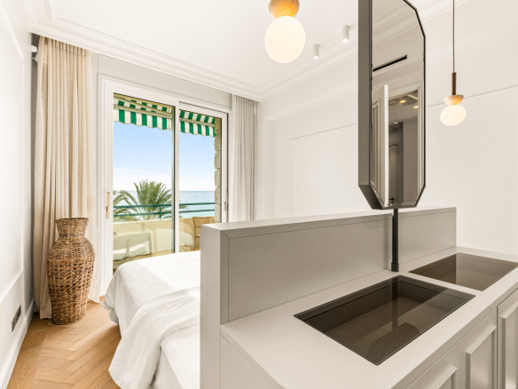 Chambre d'appartement rénové avec vue sur la mer à Nice, balcon visible.