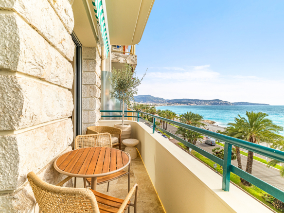 Balcon d'un appartement avec vue sur la mer Méditerranée à Nice, mobilier en bois et plantes.