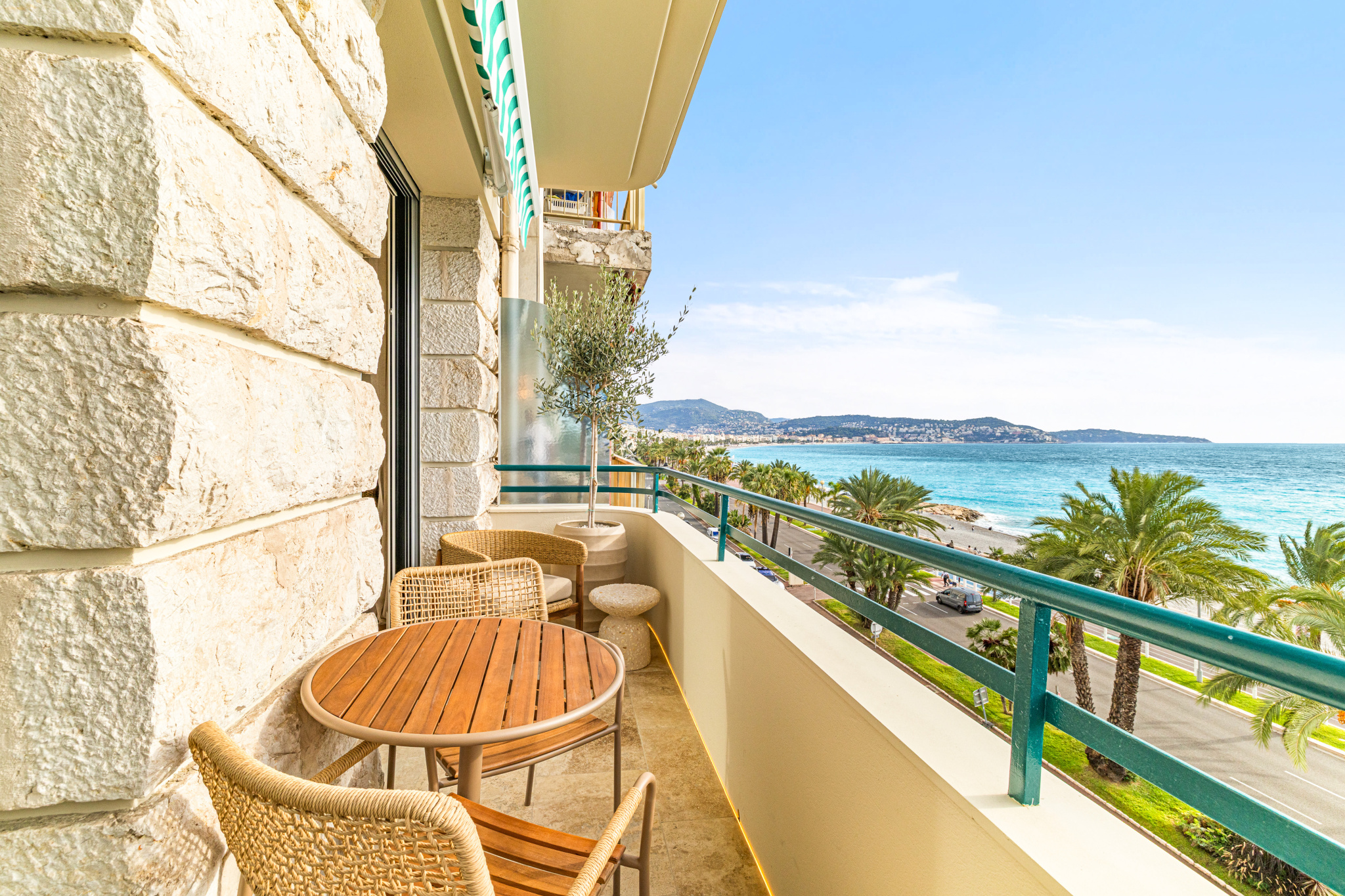 Balcon avec vue sur la Méditerranée à Nice Balcon d'un appartement avec vue sur la mer Méditerranée à Nice, mobilier en bois et plantes.