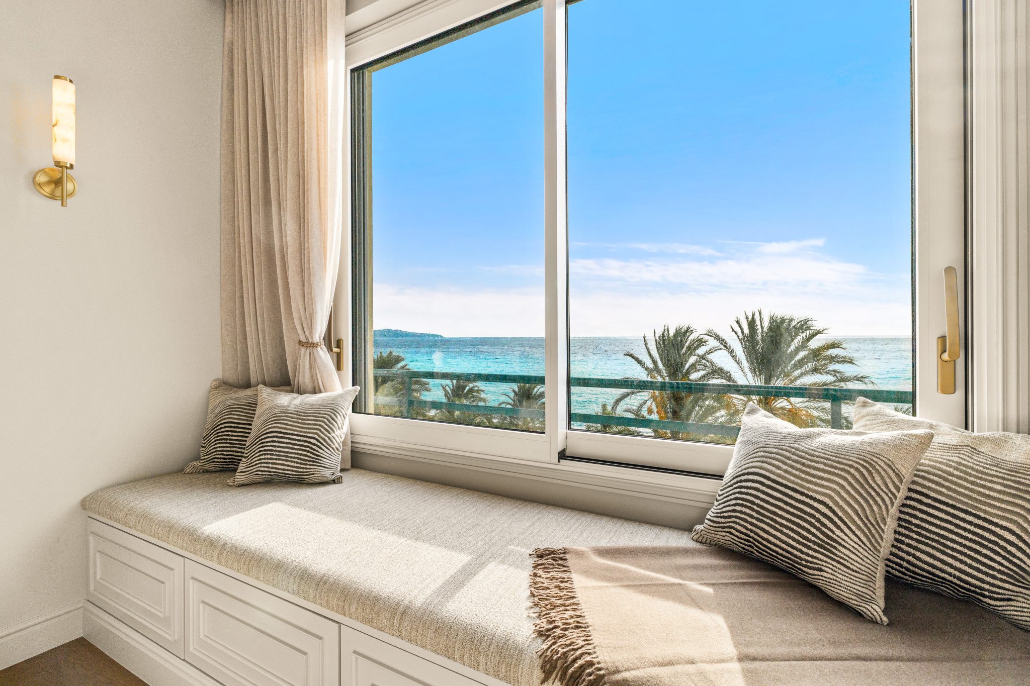 Vue panoramique sur la Méditerranée Fenêtre d'un appartement avec vue panoramique sur la mer Méditerranée et des palmiers à Nice.