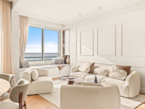 Salon lumineux avec vue sur la mer Méditerranée, mobilier moderne et fenêtres panoramiques.