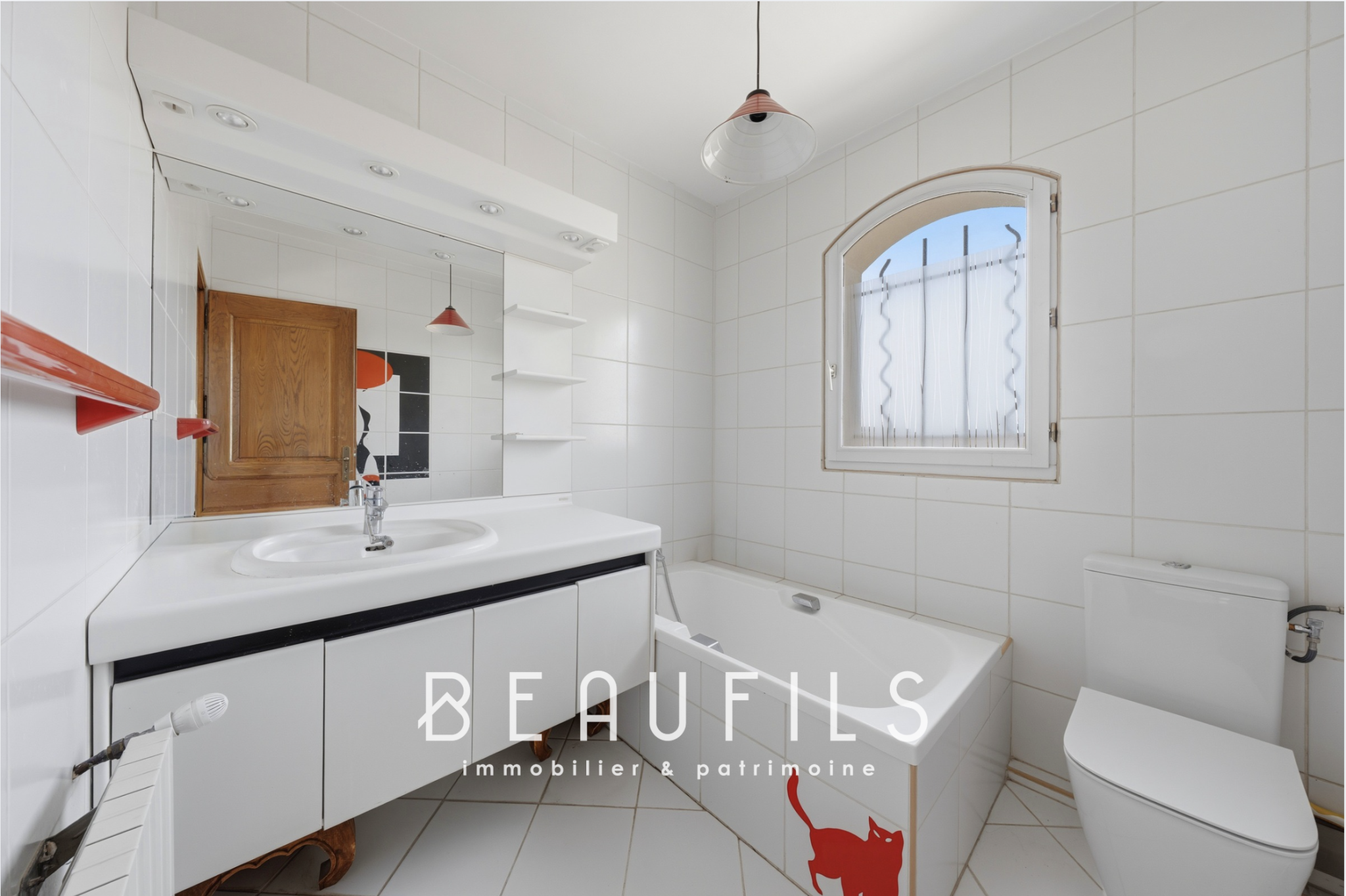 Salle de bain de la villa provençale Salle de bain avec baignoire, lavabo et toilettes, carrelage blanc, miroir et fenêtre.