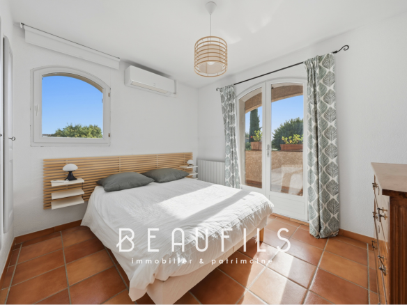 Chambre d'une villa provençale avec lit double et fenêtre offrant une vue dégagée.