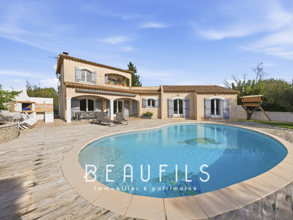 Villa provençale avec piscine et terrasse en bois, située à Lunel, dans un cadre arboré et calme.