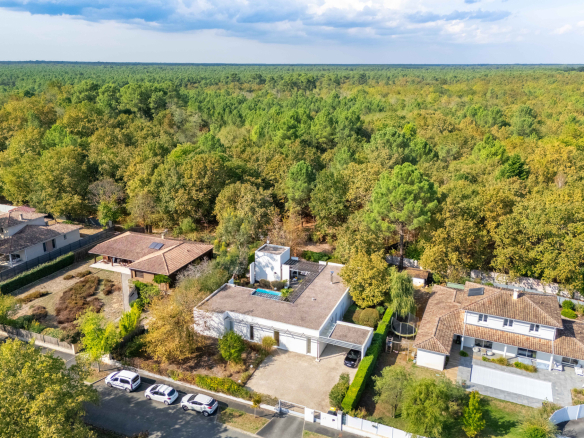 Vue aérienne d'une maison d'architecte moderne au Taillan-Médoc, entourée de verdure et de forêt.