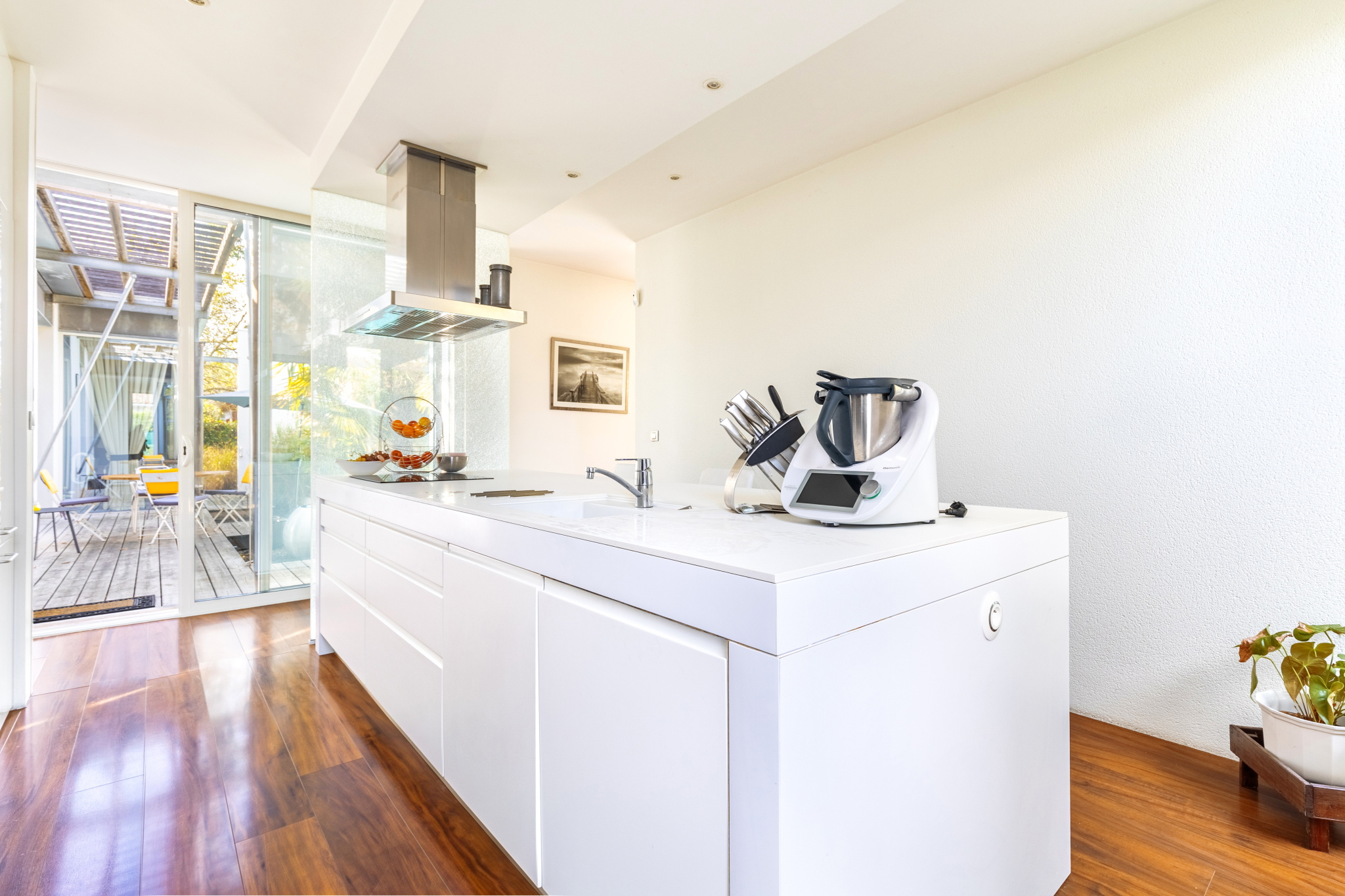 Cuisine d’une maison d’architecte au Taillan-Médoc Cuisine moderne d'une maison d'architecte avec un plan de travail blanc et un accès à l'extérieur.
