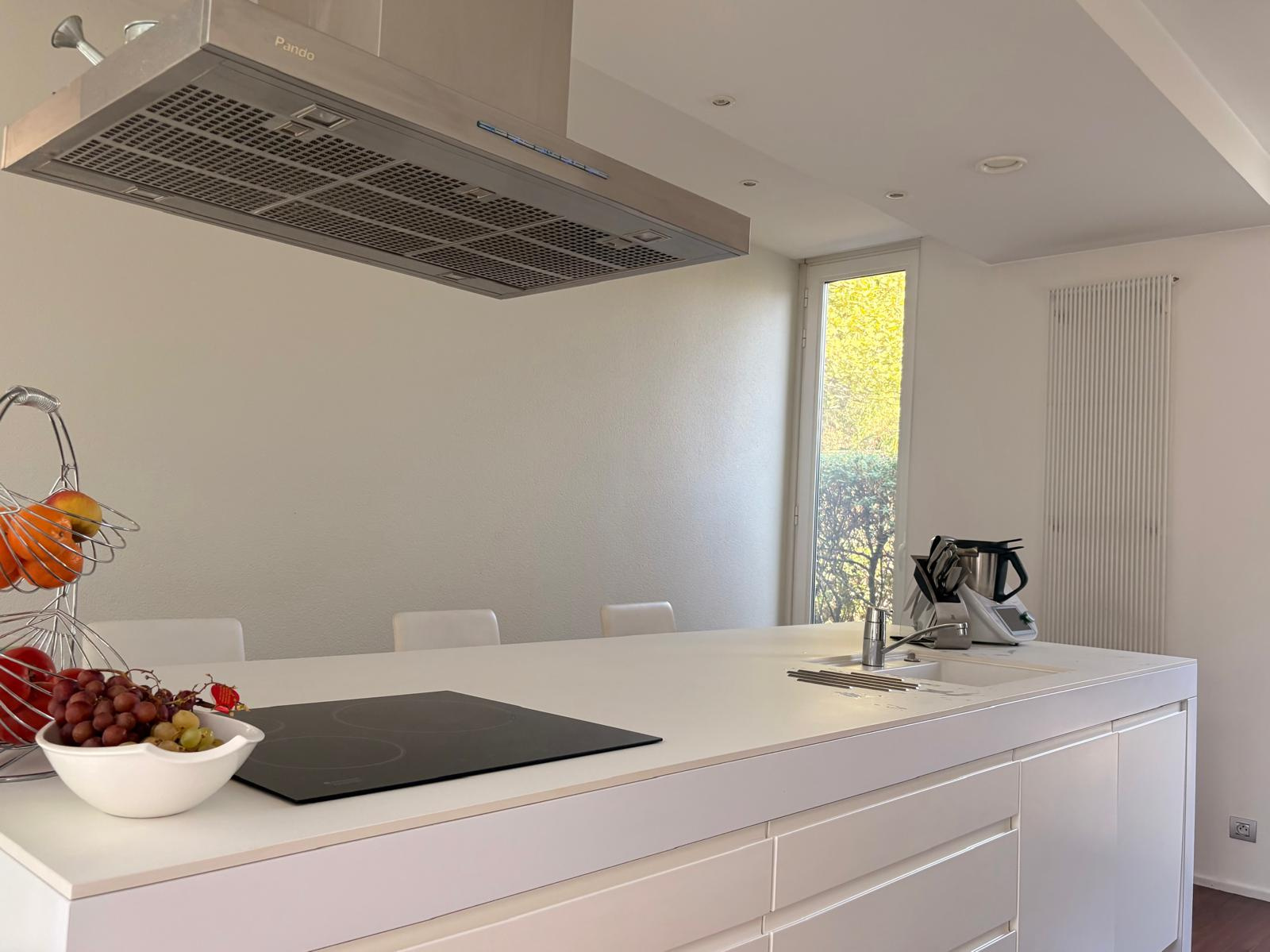 Cuisine d’une maison d’architecte au Taillan-Médoc Cuisine moderne avec un îlot central et des rangements, ouverte sur l'extérieur, dans une maison d'architecte.