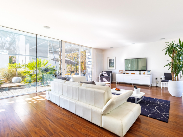 Intérieur d'une maison d'architecte moderne avec un salon lumineux et jardin visible à travers de grandes baies vitrées.
