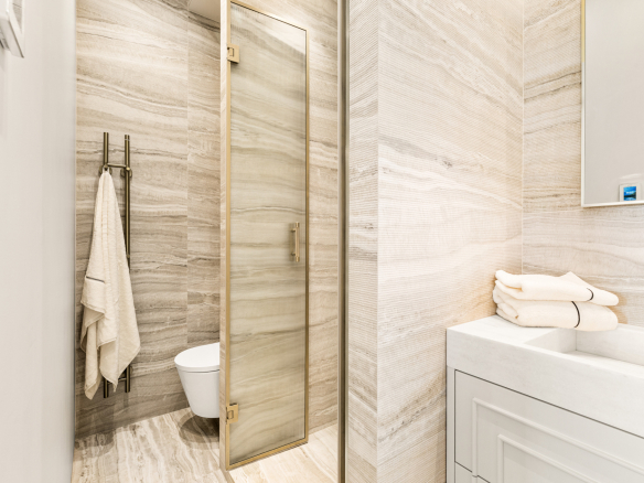 Salle de bain moderne avec douche en verre et murs en pierre naturelle.