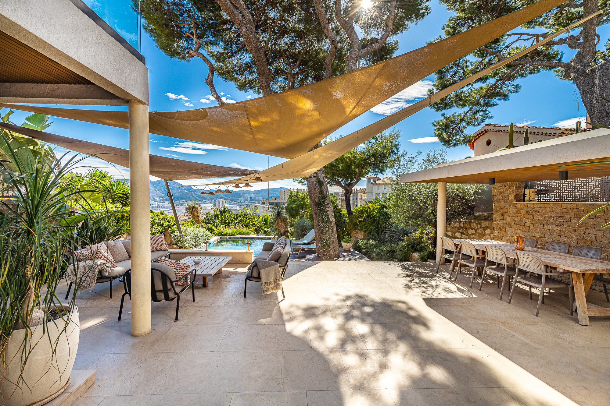 Terrasse d'une maison rénovée avec piscine et vue dégagée à Marseille, entourée de verdure.