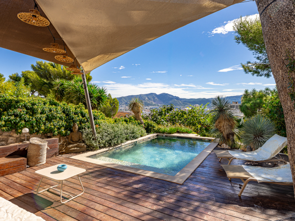 Terrasse avec piscine et chaises longues, vue dégagée sur les collines à Marseille.
