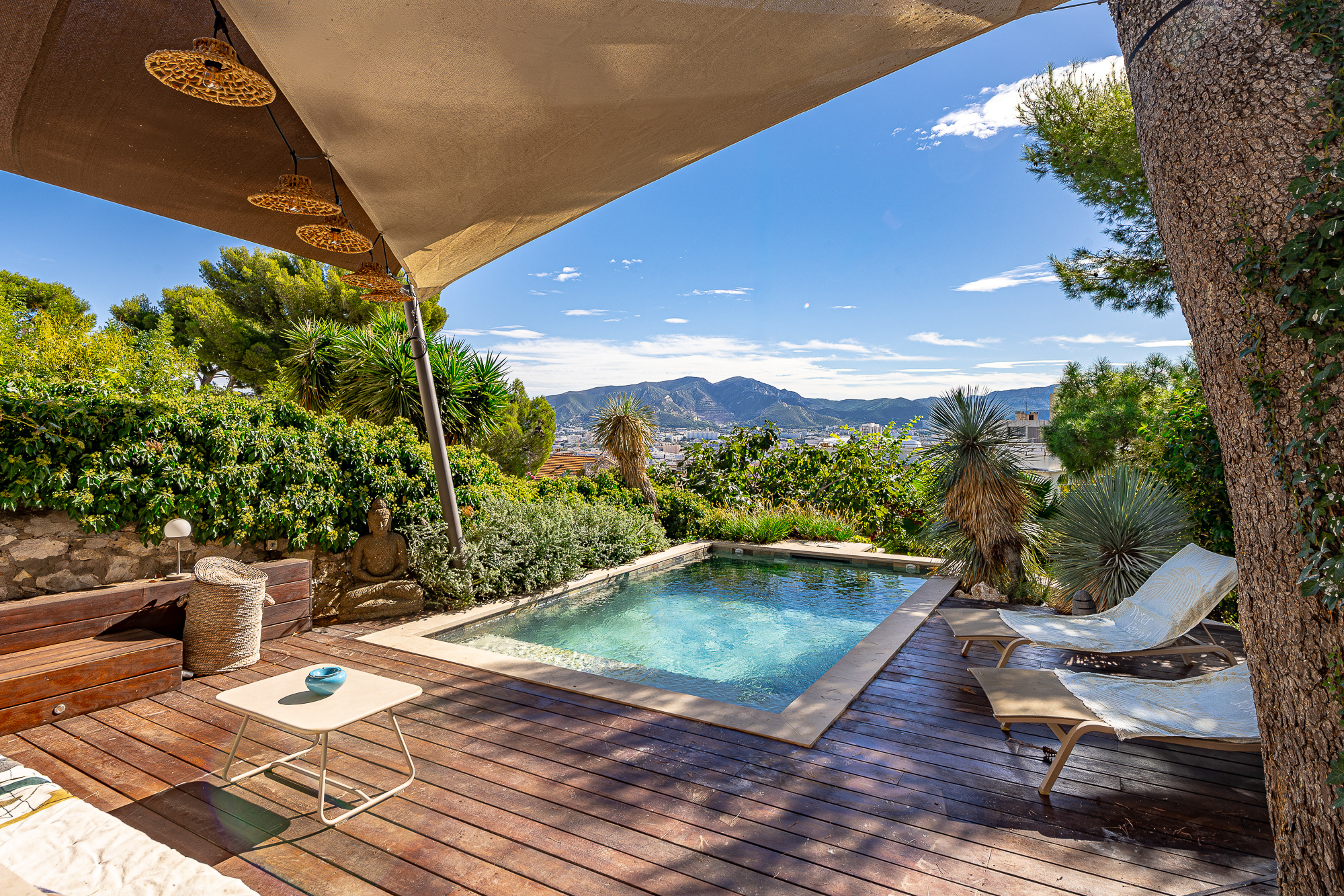 Terrasse avec piscine et chaises longues, vue dégagée sur les collines à Marseille.